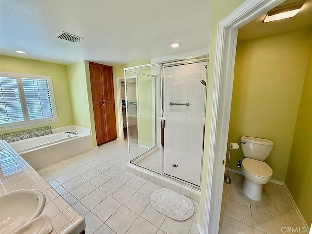 bathroom featuring tile patterned floors, toilet, a stall shower, a sink, and a bath