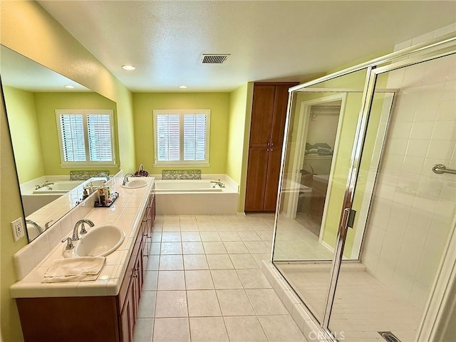 bathroom featuring double vanity, visible vents, tile patterned floors, a garden tub, and a sink