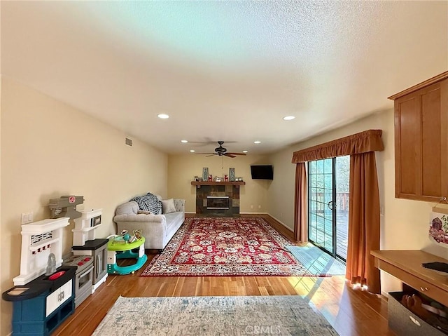 living room featuring a fireplace, recessed lighting, a ceiling fan, wood finished floors, and baseboards