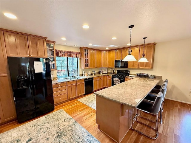 kitchen with a peninsula, black appliances, brown cabinets, and a sink