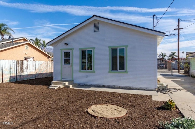 rear view of house with entry steps and fence