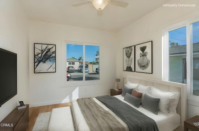 bedroom featuring ceiling fan, multiple windows, wood finished floors, and baseboards