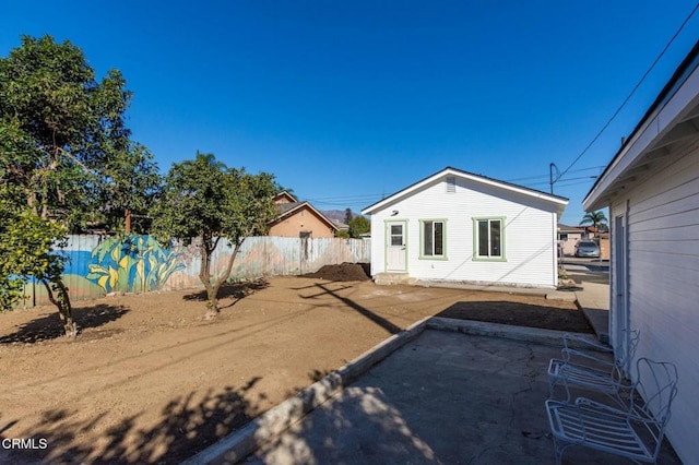 view of yard featuring an outbuilding, a fenced backyard, and a patio