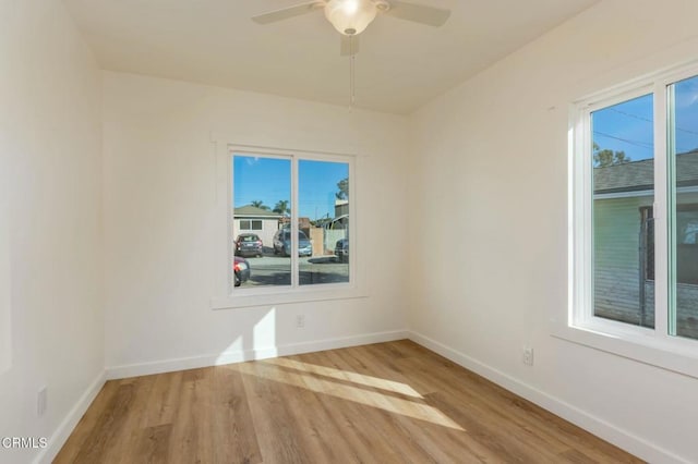 empty room with ceiling fan, wood finished floors, and baseboards