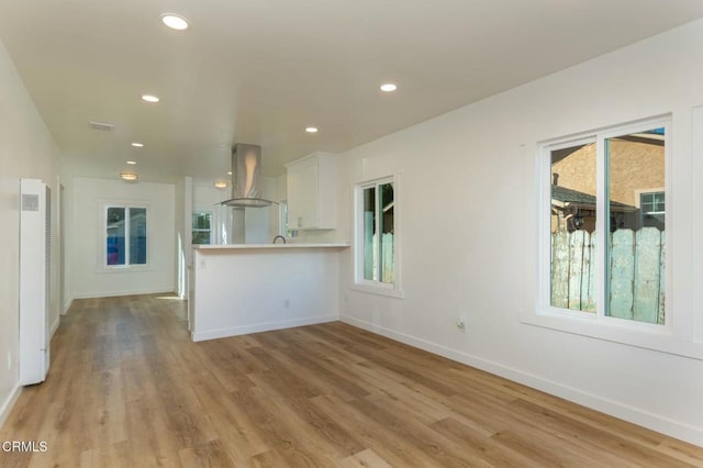 kitchen with light wood finished floors, baseboards, island range hood, and white cabinets