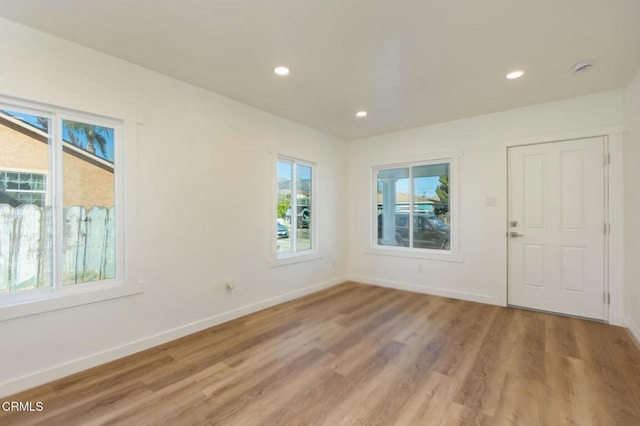 empty room featuring light wood finished floors, baseboards, and recessed lighting