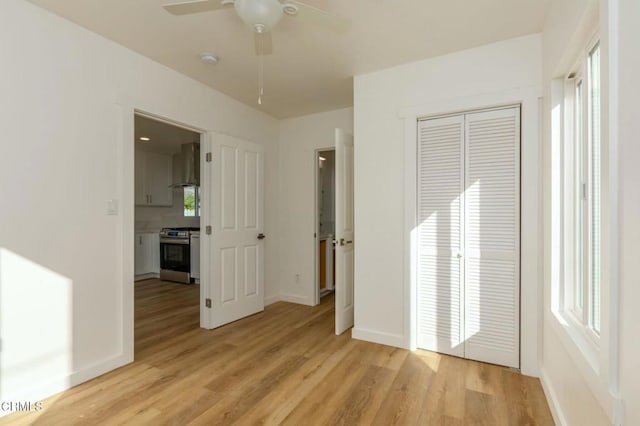 empty room featuring light wood-type flooring, a ceiling fan, and baseboards