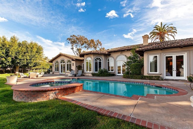 rear view of house with french doors, a chimney, stucco siding, a patio area, and a tiled roof