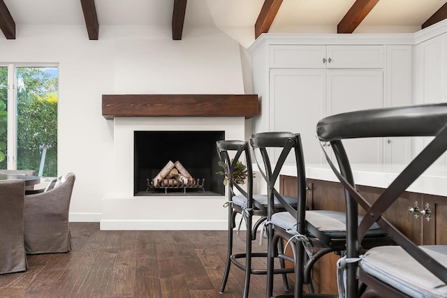 workout area featuring a fireplace with raised hearth, baseboards, and dark wood finished floors