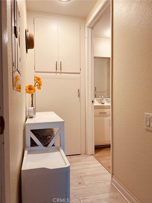 379 Avenida Castilla Unit Q, Laguna Woods, CA 92675 - clothes washing area featuring a sink, light wood-type flooring, and a textured wall