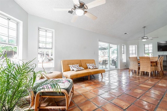 living room with a textured ceiling, visible vents, vaulted ceiling, and a ceiling fan