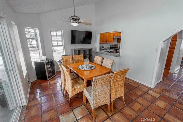 dining area featuring a textured ceiling, high vaulted ceiling, a ceiling fan, and baseboards