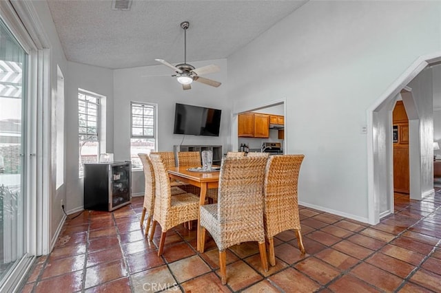 dining room with arched walkways, visible vents, a textured ceiling, and baseboards