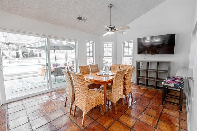 dining room featuring ceiling fan, visible vents, vaulted ceiling, and a textured ceiling