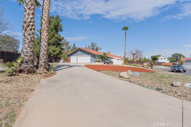 ranch-style house featuring a garage, concrete driveway, and fence