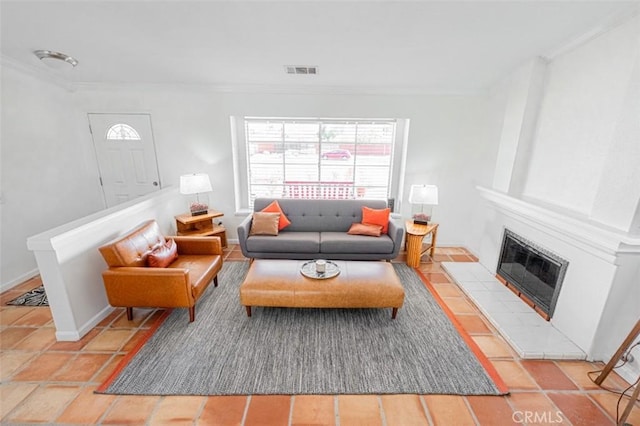 living area featuring baseboards, a tiled fireplace, visible vents, and crown molding