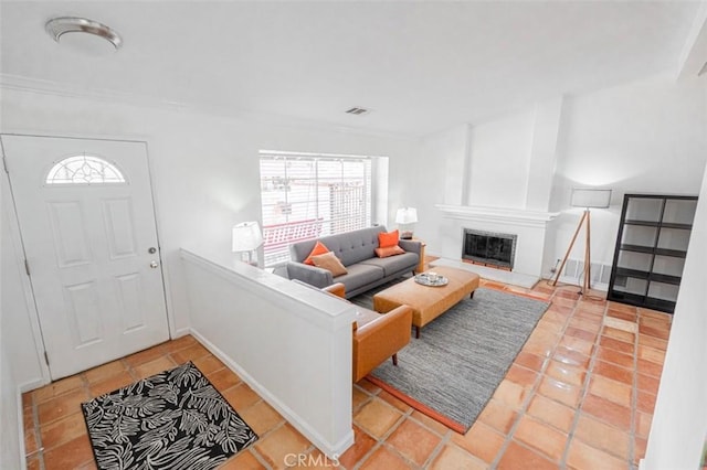 living area featuring tile patterned flooring, visible vents, baseboards, and a glass covered fireplace