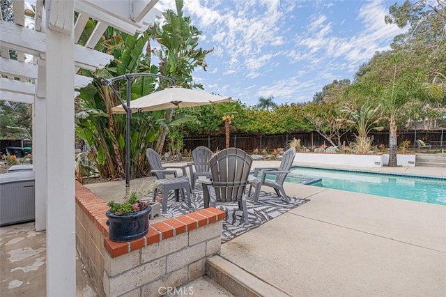 view of swimming pool with a pool with connected hot tub, a patio, and fence