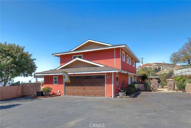 view of front facade with aphalt driveway, an attached garage, and fence