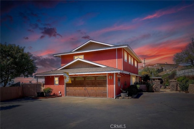 traditional-style home featuring fence, a garage, and driveway