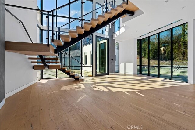 4653 Vanalden Ave, Tarzana, CA 91356 - unfurnished living room with a towering ceiling, wood-type flooring, stairs, baseboards, and floor to ceiling windows