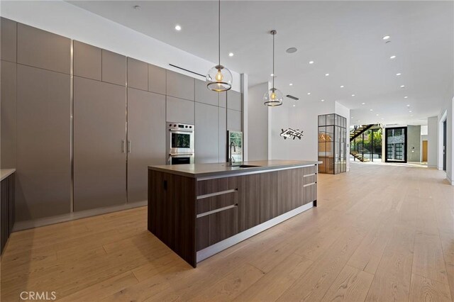 4653 Vanalden Ave, Tarzana, CA 91356 - kitchen featuring modern cabinets, light wood-style flooring, a center island with sink, open floor plan, and a sink