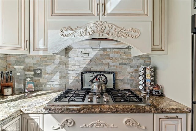 750 Zurich Dr, Lake Arrowhead, CA 92352 - kitchen with decorative backsplash, dark stone countertops, cream cabinets, and stainless steel gas stovetop