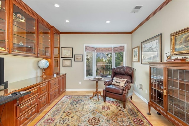 sitting room featuring ornamental molding, light wood-type flooring, visible vents, and baseboards