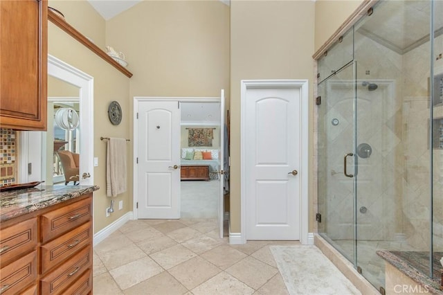 ensuite bathroom featuring baseboards, decorative backsplash, ensuite bath, vanity, and a shower stall