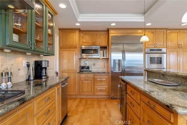 kitchen featuring built in appliances, a tray ceiling, ornamental molding, and recessed lighting