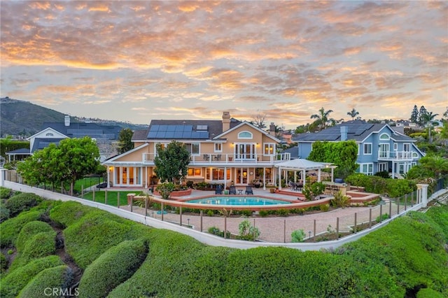 rear view of property with a fenced in pool, a fenced backyard, a gazebo, a patio area, and roof mounted solar panels