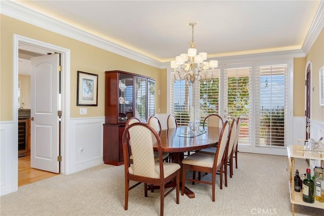 dining area with wainscoting, ornamental molding, plenty of natural light, and light colored carpet