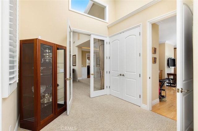 hallway featuring french doors, carpet flooring, a high ceiling, and baseboards