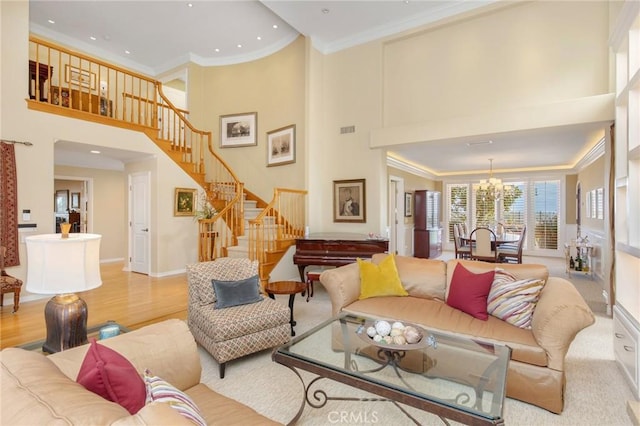 living area featuring a towering ceiling, ornamental molding, wood finished floors, stairs, and a chandelier