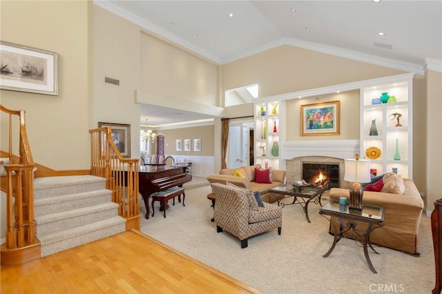 living room with visible vents, stairway, ornamental molding, a glass covered fireplace, and wood finished floors