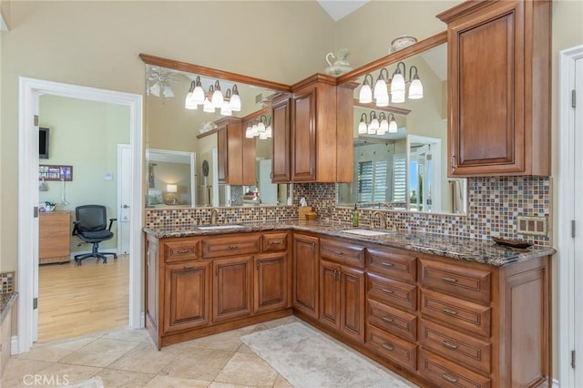 kitchen with dark stone countertops, brown cabinets, a sink, and decorative backsplash