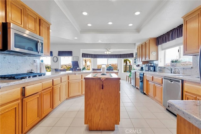 kitchen with light tile patterned floors, a tray ceiling, appliances with stainless steel finishes, and a center island