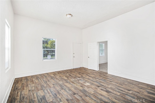 empty room featuring a textured ceiling, wood finished floors, and baseboards