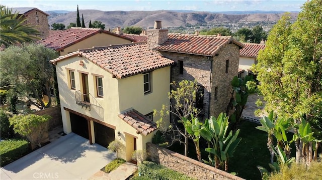 exterior space with stone siding, a tile roof, concrete driveway, and stucco siding