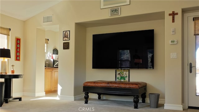 interior space featuring light colored carpet, visible vents, vaulted ceiling, and baseboards