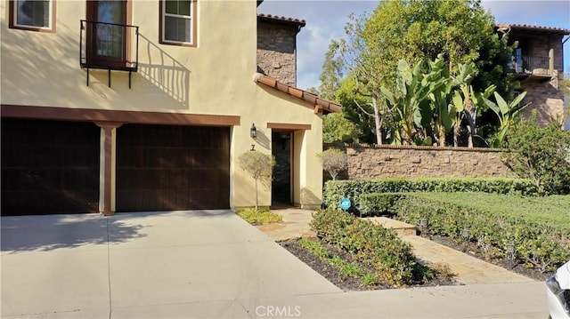 view of front facade featuring stucco siding, concrete driveway, a garage, stone siding, and a tiled roof