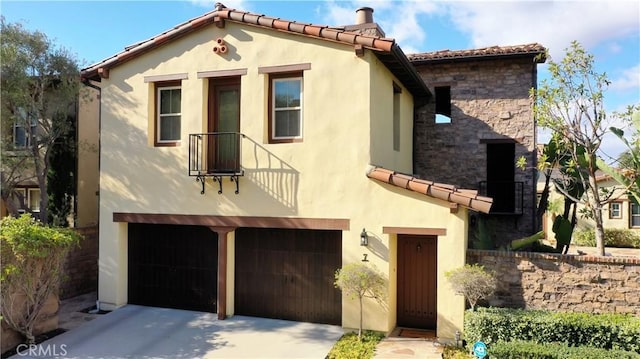 mediterranean / spanish house with stone siding, a tile roof, concrete driveway, and stucco siding