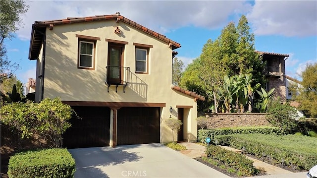 mediterranean / spanish house with an attached garage, a tiled roof, concrete driveway, and stucco siding