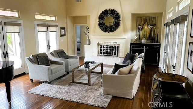 living room with french doors, a high ceiling, a fireplace, and dark wood-style flooring