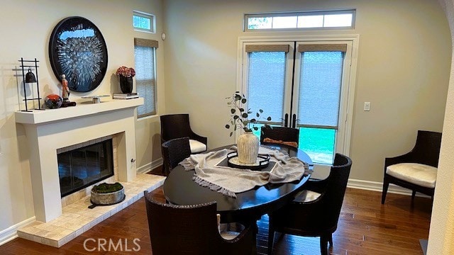 dining area with a tile fireplace, baseboards, and wood finished floors