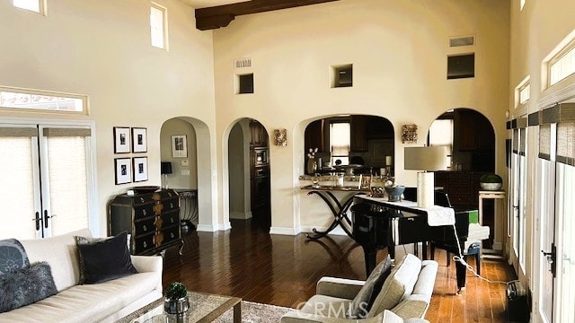 living room with arched walkways, a high ceiling, baseboards, and wood finished floors