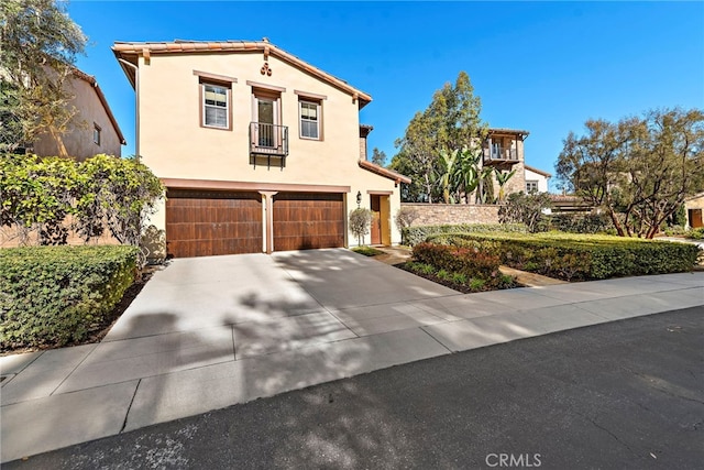 mediterranean / spanish home with concrete driveway, an attached garage, and stucco siding