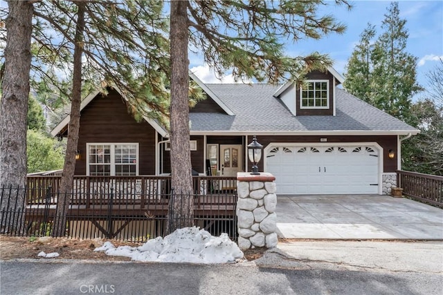 view of front of property featuring a shingled roof, concrete driveway, covered porch, fence, and a garage