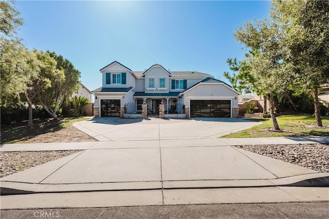 craftsman-style home featuring driveway, stone siding, and stucco siding