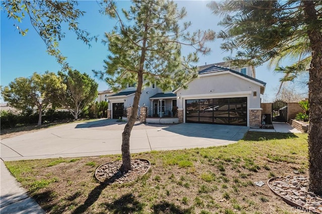 view of front facade with a garage, stone siding, driveway, a gate, and stucco siding